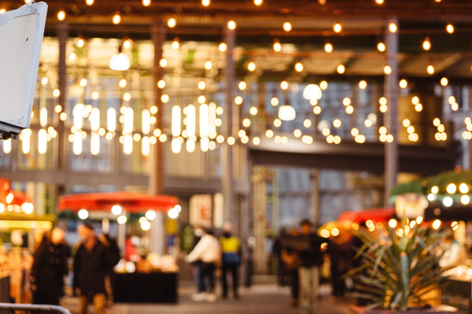 Étals d'un marché nocturne d'été éclairés par des guirlandes lumineuses